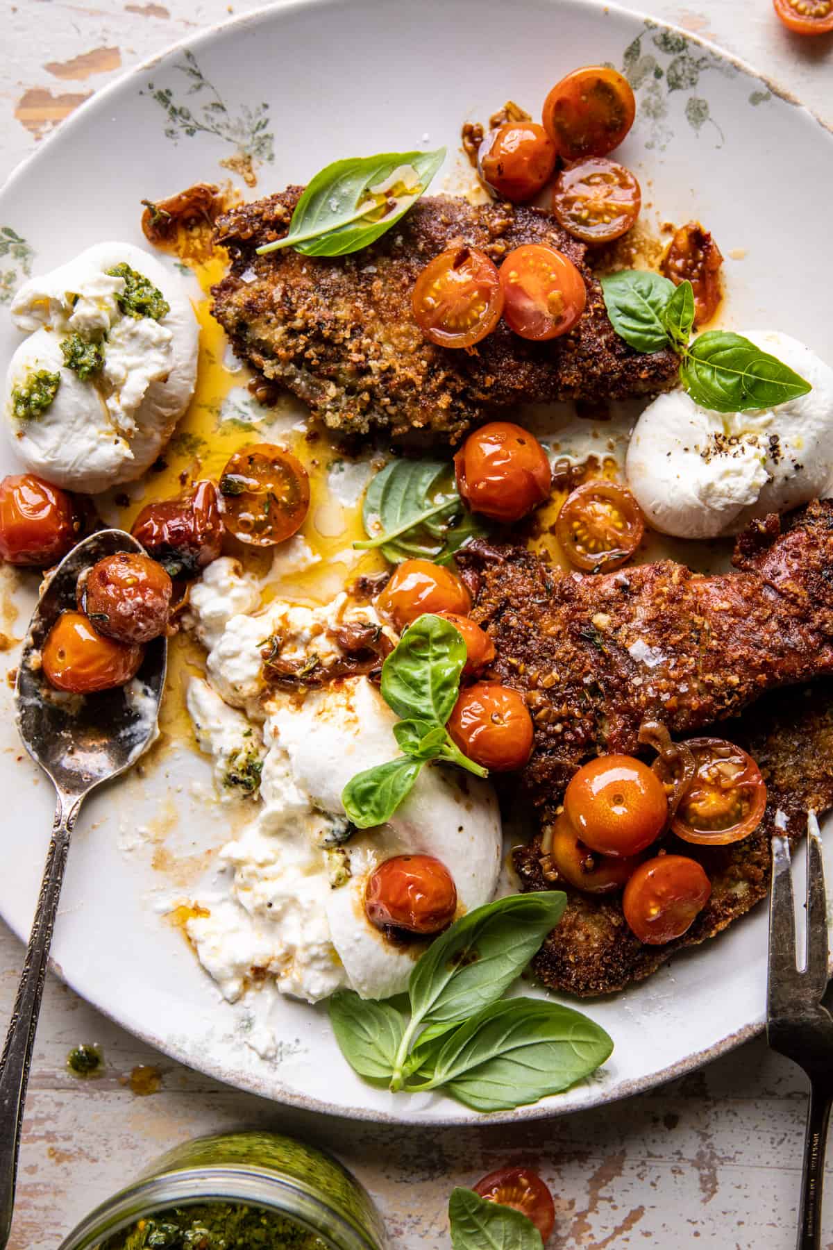 Crispy pesto and prosciutto wrapped chicken cutlets with burst cherry tomatoes, torn burrata and fresh basil
