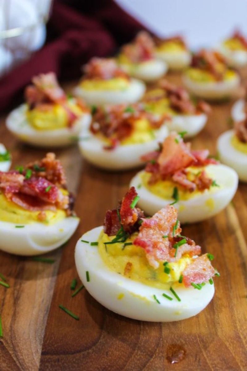 Classic deviled eggs with fresh dill and candied bacon on a platter