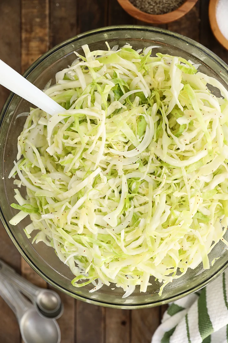Tangy vinegar slaw with shredded cabbage and sweet onion in a large bowl