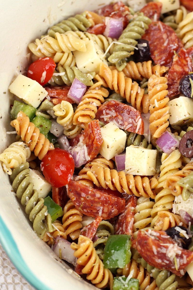 Tangy Italian pasta salad with tri-color rotini, pepperoni, mozzarella and olives in a large bowl
