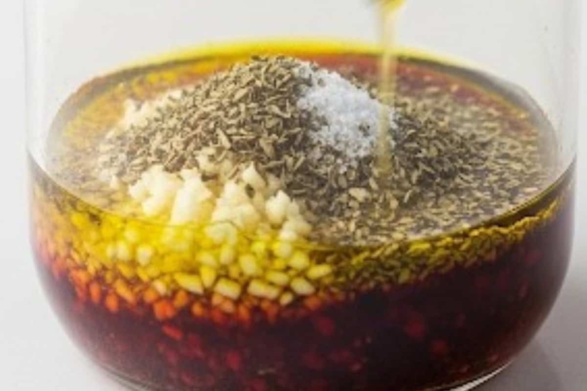 Homemade Greek salad dressing in a small jar with olive oil and oregano